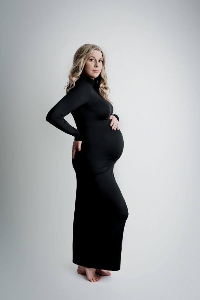 Expecting mother wearing a long black dress looking at the camera