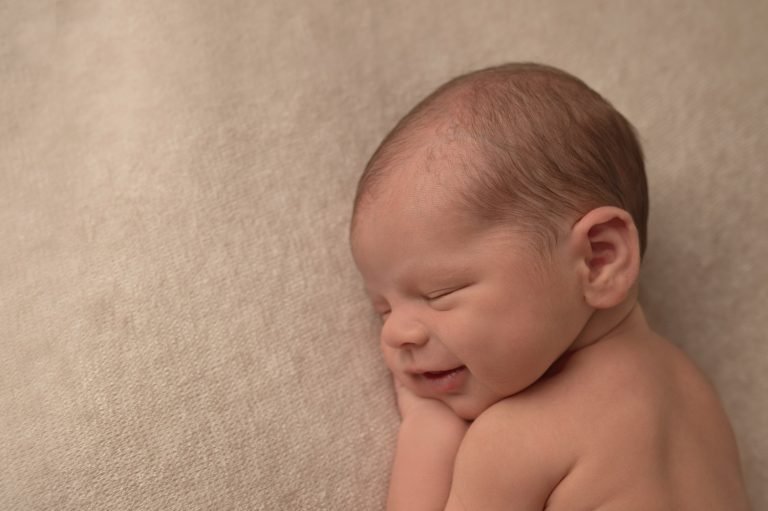 profile view of a newborn smiling in his sleep