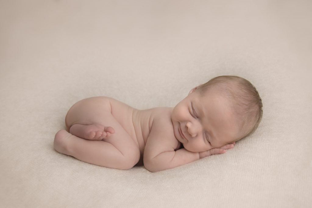 Newborn sleeping in a bum up pose smiling