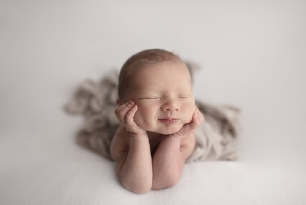 Sleeping smiling newborn propped on his hands