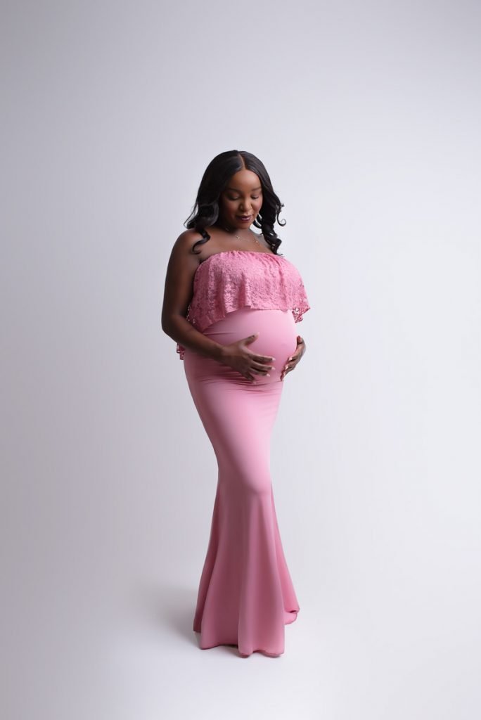 Expecting mom to be wearing a rose coloured dress and looking at her baby bump