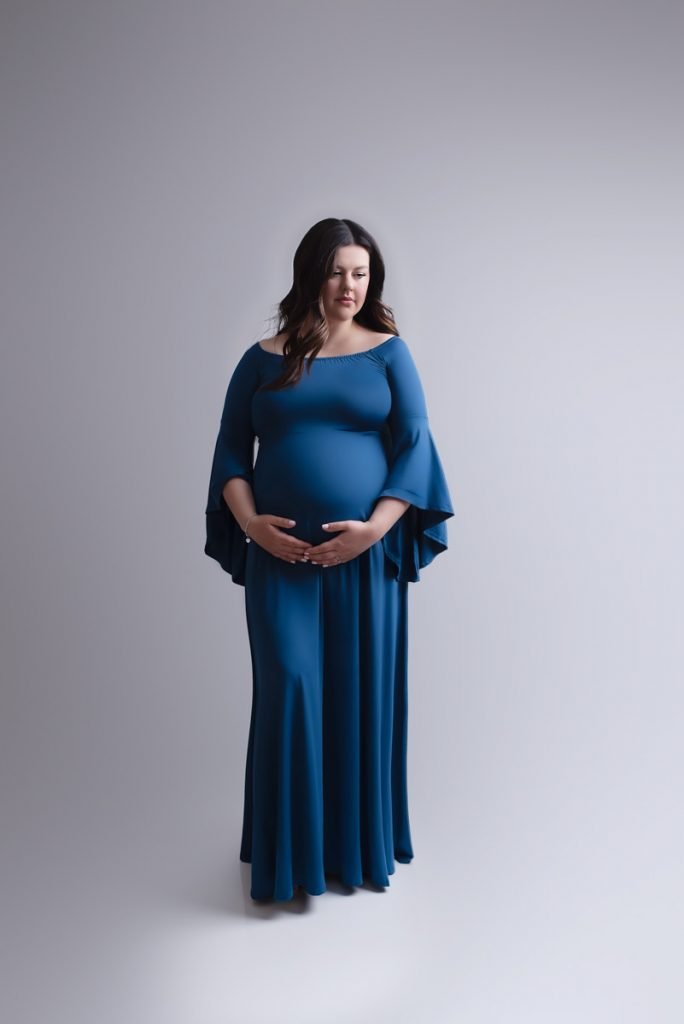 Pregnant woman posing in a blue dress