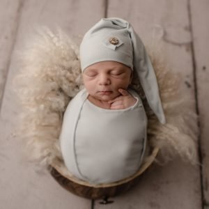 Newborn Baby Boy posed in a bucket with a light blue sleepy hat - shot taken by a professional newborn photographer