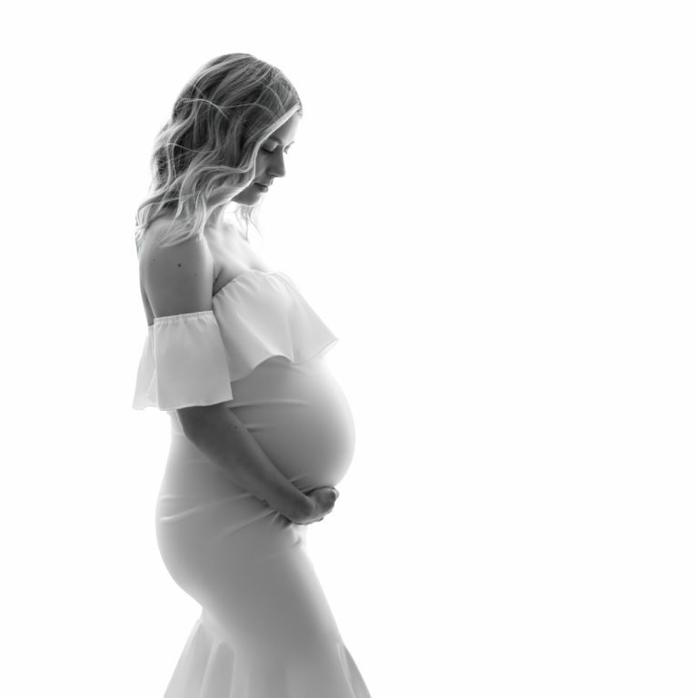 Vancouver Maternity Photo Shoot - Side profile of pregnant woman in white dress looking down on her baby bump