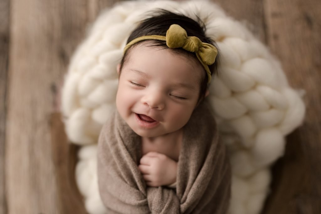 Newborn Photography North Vancouver - Newborn girl laughing wearing a green bow