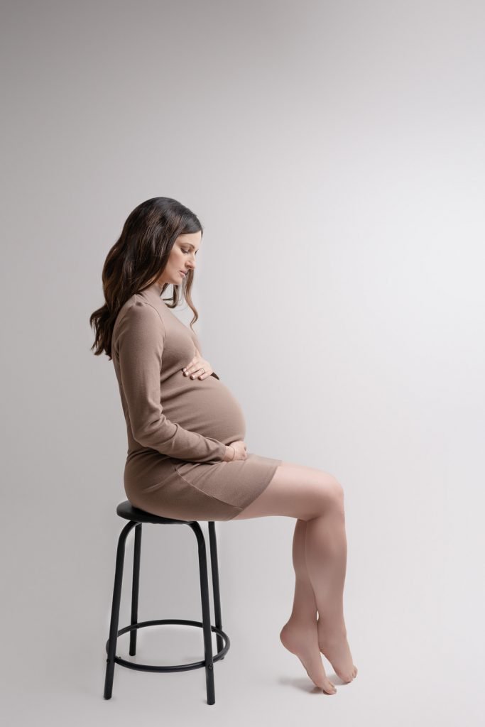 Vancouver Pregnancy photo shoot woman wearing a beige short dress looking at her belly