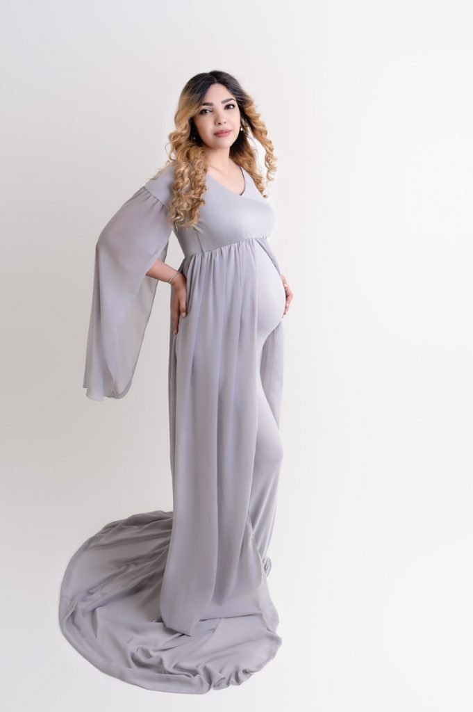 Vancouver Maternity Photography pregnant woman wearing a grey flown dress smiling at the camera