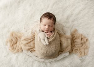 Vancouver Newborn Photographer baby boy holding a bunny while sleeping in a whit wooden bowl