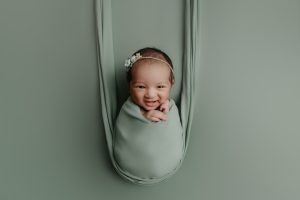 Newborn Photography Vancouver - baby girl smiling on sage backdrop
